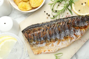 Tasty roasted mackerel with spices and potatoes on white marble table, flat lay. Homemade seafood dish