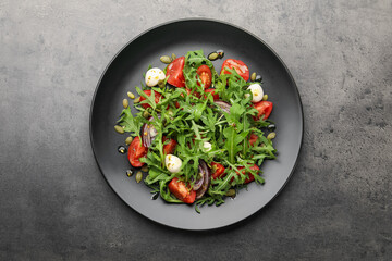 Tasty salad with arugula, mozzarella and vegetables on grey table, top view