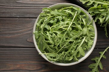Fresh ripe green arugula leaves on dark wooden table, flat lay. Space for text