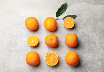 Fresh ripe oranges and green leaves on grey table, flat lay