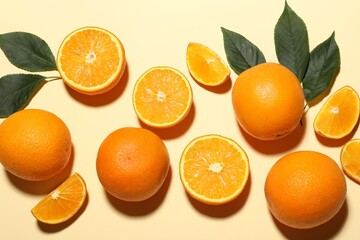 Fresh ripe oranges and green leaves on beige background, flat lay