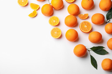 Fresh ripe oranges and green leaves on white background, flat lay. Space for text