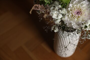 Beautiful flowers in vase on wooden table, closeup. Space for text