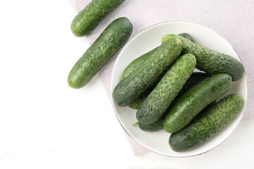 Fresh cucumbers in bowl on white table, flat lay