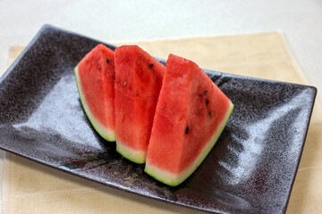 黒皿に並べられた三角形にカットされたスイカ