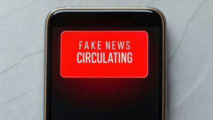 A smartphone screen displays a bold red alert with the message "FAKE NEWS CIRCULATING" against a gray textured background.