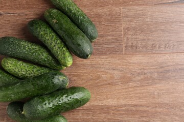 Fresh cucumbers on wooden table, flat lay. Space for text