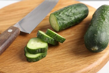 Slices of fresh cucumber and knife on white table, closeup