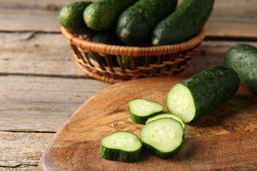 Cut and whole cucumbers on wooden table, closeup