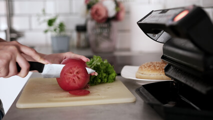 Girl Slices Tomatoes For Burger At Home In Kitchen