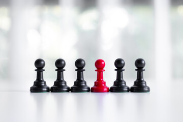 Red chess pawn standing out among black pawns. Concept of uniqueness, leadership, and distinction....