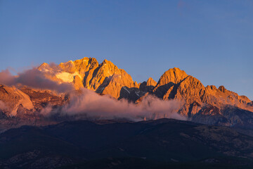 Naklejka premium The view of Yulong Snow Mountain bathed in sunlight on the golden Mountain