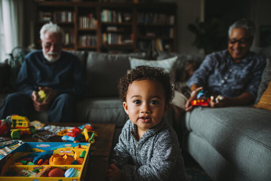 Boy plays with grandparents, smiling indoors. Illustrates family, relationships, childhood, growth. Suitable for marketing, design, or website imagery. - Powered by Adobe