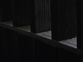 close up view of dark wooden planks with textured surface, showcasing interplay of light and shadow. image highlights natural grain and depth of wood