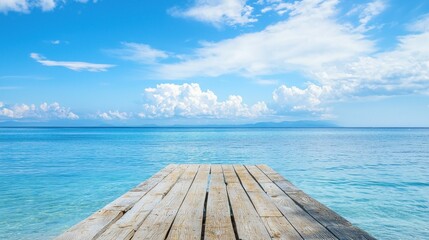 A wooden pier extending into a calm blue sea with a clear blue sky above.