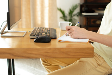 young man in a yellow t-shirt works at home at the computer. chat online. remote work via the...