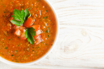 Cold summer soup Gazpacho in a white bowl on the table. Traditional Spanish cuisine concept. Vegan or vegetarian. Selective focus. Horizontal orientation. Top view. Copy space.