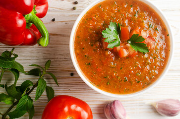 Cold summer soup Gazpacho in white bowl with ingredients on table. Traditional Spanish cuisine concept. Vegan or vegetarian. Selective focus. Horizontal orientation. Top view.