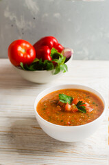 Cold summer soup Gazpacho in white bowl with ingredients on table. Traditional Spanish cuisine concept. Vegan or vegetarian. Selective focus. Vertical orientation.