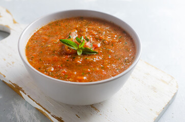 Cold summer soup Gazpacho in a gray bowl on a gray background. Traditional Spanish cuisine concept. Vegan or vegetarian. Selective focus. Horizontal orientation.