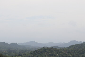 Serene Mountain Vista: A tranquil and expansive vista unveils rolling mountains under a soft, muted sky, embodying peace.