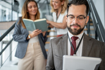 Businessman using digital tablet on stairs in office with colleagues reading