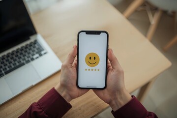 A person at a desk gives a five-star satisfaction rating on a smartphone, providing positive feedback for an excellent online service.