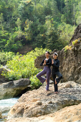 Asian Indonesian Women Doing Yoga Exercise in Nature on Rocky Riverside