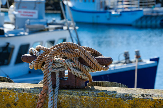 Commercial lobster boat moored at a dock at a Nova Scotia harbor with the bollard holding the tie down ropes
