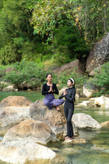 Asian Indonesian Women Practicing Yoga and Meditation by the River in Nature