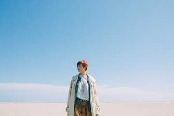 Fototapeta premium person standing alone in vast open space dressed in eclectic mix of vintage and modern clothing beneath clear blue