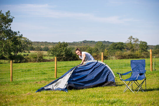 woman pitching a tent on a campsite