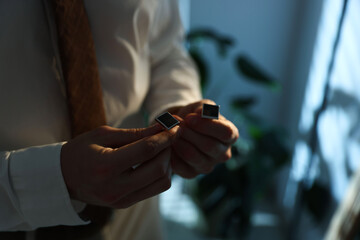 Man with cufflinks getting ready indoors, closeup. Space for text