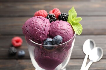 Delicious sorbet with fresh berries and mint in glass dessert bowl on wooden table, closeup