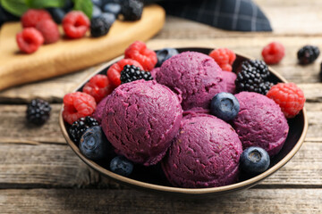 Delicious sorbet with fresh berries in bowl on wooden table, closeup
