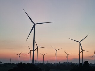 Wind Turbines at Dusk: A mesmerizing silhouette of wind turbines against a vibrant evening sky, symbolizing sustainable energy and environmental consciousness.