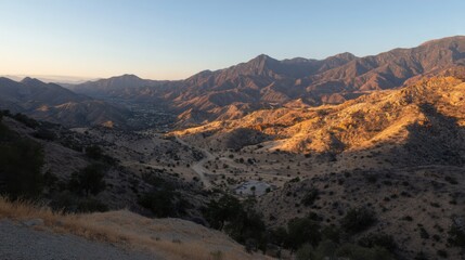 Fototapeta premium Panoramic view of rugged mountain terrain at sunrise or sunset, warm light accentuating contours,