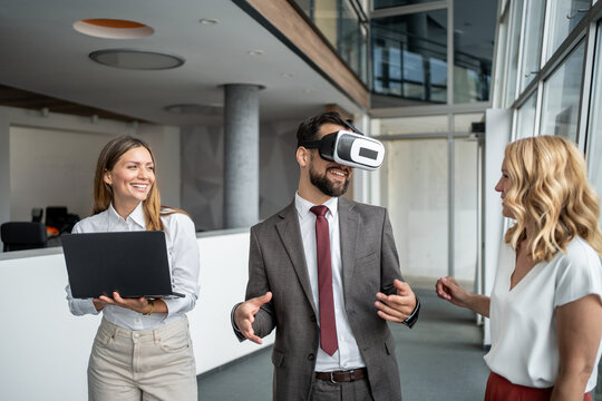 Businessman experiencing virtual reality with colleagues in modern office - Powered by Adobe