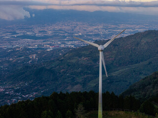 Beautiful aerial view of wind Mills - turbines- on Costa Rica&rsquo;s hills at sunset, overlooking San Jos&eacute; city with vibrant skies, renewable energy, and a stunning mountain landscape