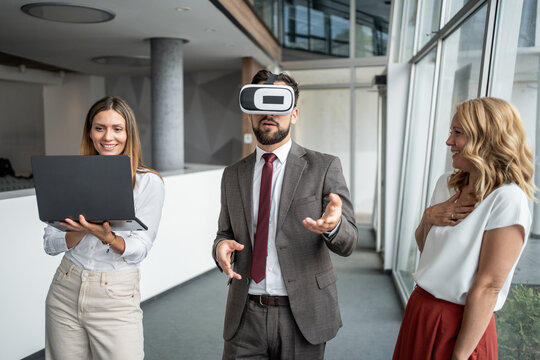 Businessman wearing vr headset interacting with colleagues in modern office