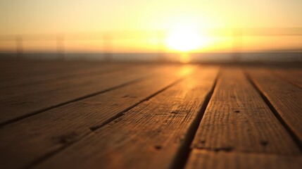 Close up of weathered wooden planks on a pier leading to a glowing sunrise or sunset over calm water,