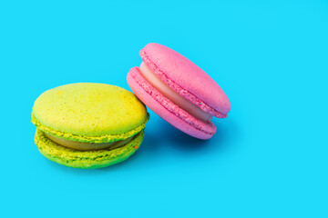 Mixed of colorful macaroni or pasta cake on a blue background. Sweet and colorful french macarons. Two multi-colored green and pink macaroons. Culinary and cooking concept, styling food.