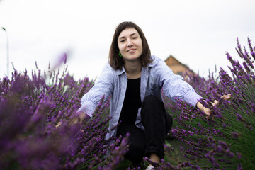 Beautiful 28-year-old brunette woman with bob haircut sitting in blooming lavender field on a summer day, peaceful mood, natural lifestyle