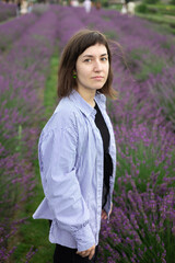 Beautiful 28-year-old brunette woman with bob haircut sitting in blooming lavender field on a summer day, peaceful mood, natural lifestyle