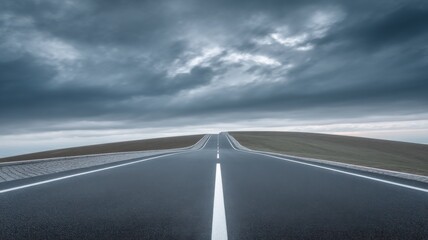 Naklejka premium A solitary road stretches into the distance under an overcast sky, smooth with clear white markings,