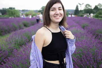 Beautiful 28-year-old brunette woman with bob haircut sitting in blooming lavender field on a summer day, peaceful mood, natural lifestyle
