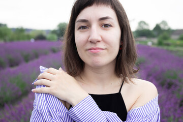 Beautiful 28-year-old brunette woman with bob haircut sitting in blooming lavender field on a summer day, peaceful mood, natural lifestyle