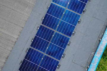 Vue a&eacute;rienne de panneaux photovolta&iuml;ques install&eacute;s sur le toit d&rsquo;un b&acirc;timent industriel sous un ciel d&eacute;gag&eacute;.
