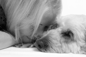 Black and white close-up of a woman gently resting her face against her sleeping dog, showing a calm and emotional bond between human and pet