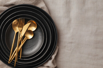 Gold flatware rests on black plates. Image ideal for kitchenware marketing, food design, or a lifestyle blog.